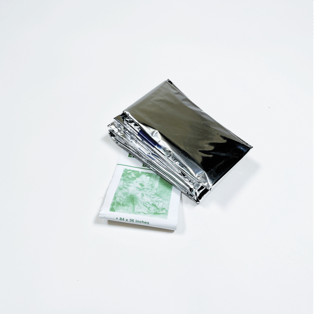 Harmaan kiiltävä avaruuspeitto taiteltuna valkoisella taustalla.